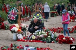 A Russian navy officer lights a candle as he pays his last respect at the grave of Captain 3rd rank Vladimir Sukhinichev, one of the 14 crew members who died in a fire on a Russian navy's deep-sea research submersible.