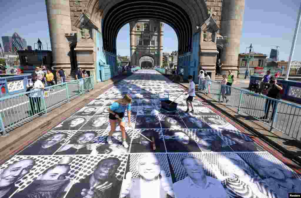 Workers place portraits of Londoners, including London&#39;s Mayor Sadiq Khan, by French artist JR, on the road at Tower Bridge to celebrate UEFA Euro 2020, in London.