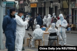 Workers in protective suits help residents in their transfer to a quarantine facility following new infections of COVID-19, near Renji Hospital Affiliated with Shanghai Jiao Tong University Medical School in Shanghai on Jan. 21, 2021.