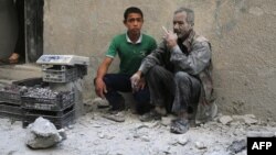 A man covered with dust sits on a street following a reported airstrike by Syrian government forces in the rebel-held neighborhood of Sukkari in the northern city of Aleppo, May 30, 2016.