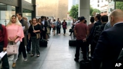 FILE - Immigrants awaiting deportation hearings line up outside the building that houses the immigration courts in Los Angeles, June 19, 2018.