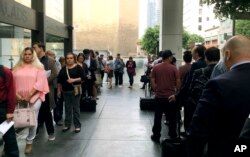 FILE - Immigrants awaiting deportation hearings line up outside the building that houses the immigration courts in Los Angeles, June 19, 2018.