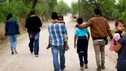 FILE - Migrant families walk from the Rio Grande, the river separating the U.S. and Mexico, near McAllen, Texas, March 14, 2019. The Department of Homeland Security said Dec. 23, 2021, that 100 children separated from parents during the Trump administration had been reunited with their families.