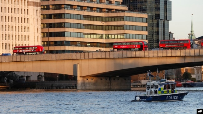 一艘英国警方船只从泰晤士河上向伦敦桥驶去。枪击事件发生后伦敦桥上停放着被丢弃的公共汽车。（2019年11月29日）