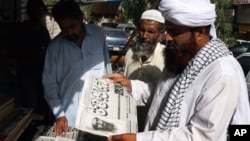 People read newspapers at a news stand carry headlines "Osama bin Laden killed." in Hyderabad, Pakistan on Monday, May 2, 2011.