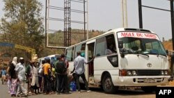 ARCHIVES - Des passagers attendent en queue pour embarquer dans un bus garé à Akanyaru du côté rwandais d'une rue située à la frontière avec le Burundi, le 23 août 2016.