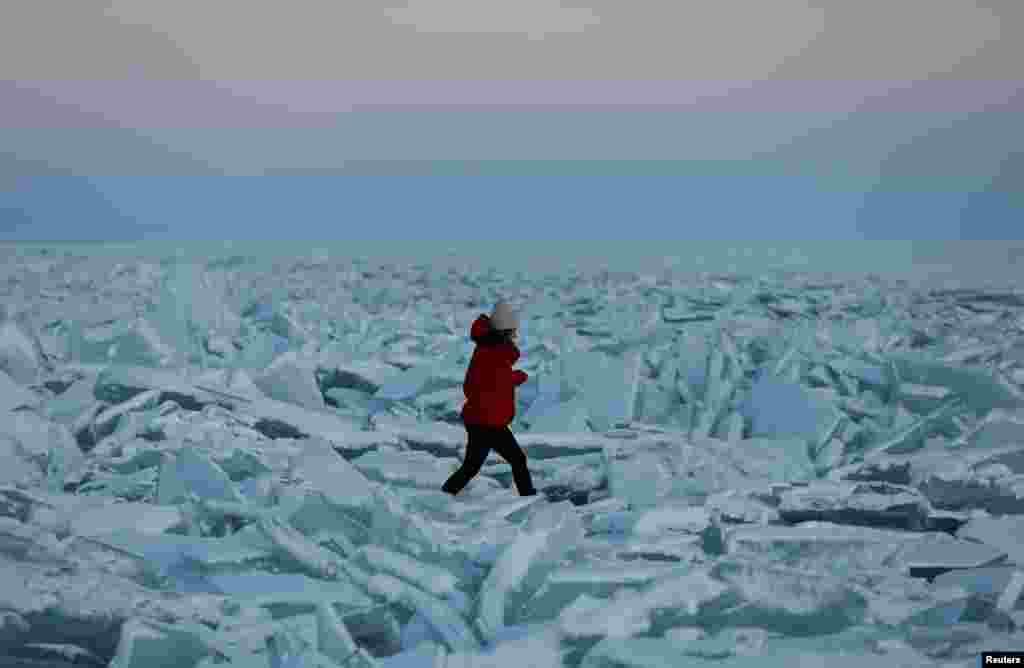 A woman walks through pieces of ice on the frozen Kapchagay reservoir outside Almaty, Kazakhstan.