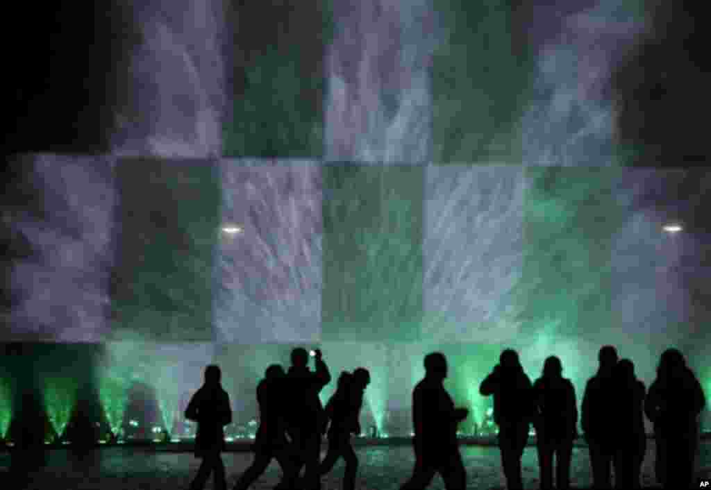 People are silhouetted as they watch a night fountain show with color lights near the Centennial Hall in Wroclaw, Poland, Thursday, Oct. 7, 2010.(AP Photo/Alik Keplicz)