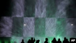 People are silhouetted as they watch a night fountain show with color lights near the Centennial Hall in Wroclaw, Poland, Thursday, Oct. 7, 2010.(AP Photo/Alik Keplicz)