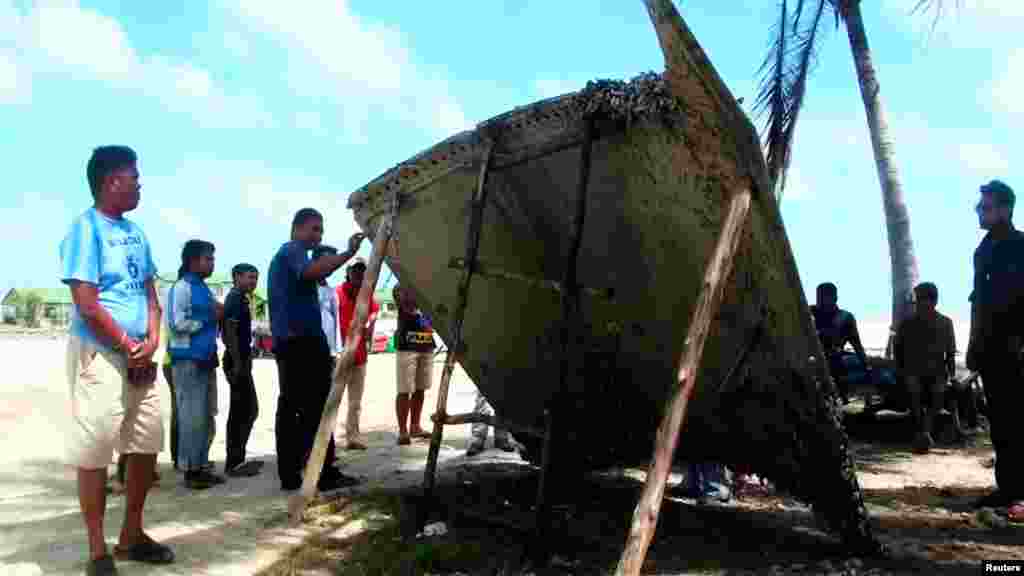 People stand next to a piece of suspected plane wreckage which has been found off the coast of southern Thailand in Nakhon Si Thammarat province, Jan. 24, 2016. 