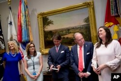 White House press secretary Sarah Sanders, right, accompanied by, from left, presidential counselor Kellyanne Conway; Mercedes Schlapp, director of strategic communications; deputy press secretary Hogan Gidley; and White House chief economic adviser Larry Kudlow, speaks after President Donald Trump asked her how his demeanor was during Wednesday's infrastructure meeting with House Speaker Nancy Pelosi, May 23, 2019.