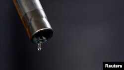 A drop of diesel is seen at the tip of a nozzle after a fuel station customer fills her car's tank in Sint Pieters Leeuw, Dec. 5, 2014. 