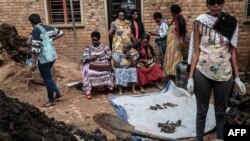 Une photo prise le 30 avril 2018 montre des personnes qui ramassent les ossements des victimes dans une fosse commune à Kabuga, dans la banlieue de Kigali au Rwanda. Selon l'association principale des survivants du génocide, IBUKA, le mot signifie «souviens-toi» en kinyarwanda /