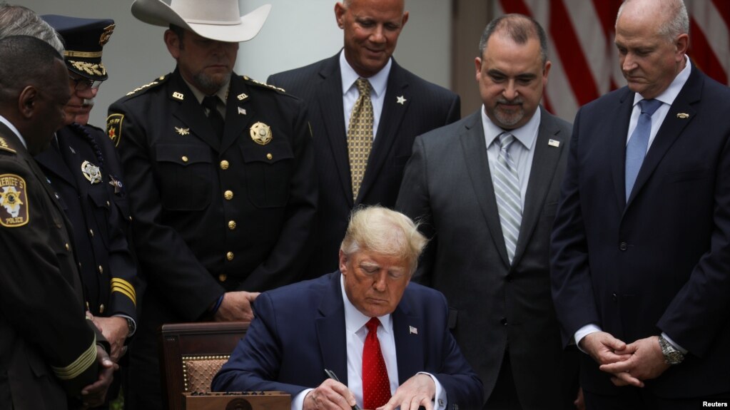 U.S. President Donald Trump signs an executive order on police reform while surrounded by law enforcement leaders during an event in the Rose Garden at the White House in Washington, U.S., June 16, 2020. REUTERS/Leah Millis