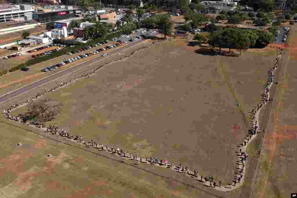A line of people snakes around a field to enter a COVID-19 vaccination site, as people over age 30 became eligible for a vaccine in Brasilia, Brazil.