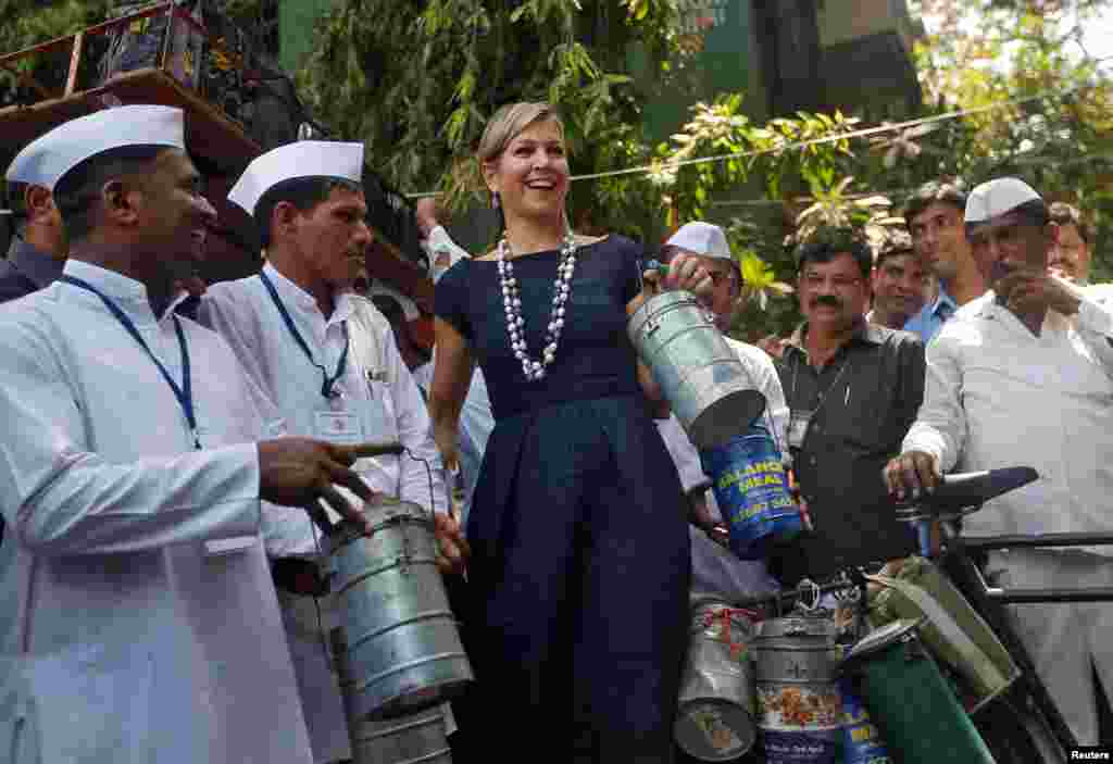 Queen Maxima of the Netherlands holds a tiffin as she poses with Dabbawalas, also known as tiffin carriers, during their meeting in Mumbai, India.