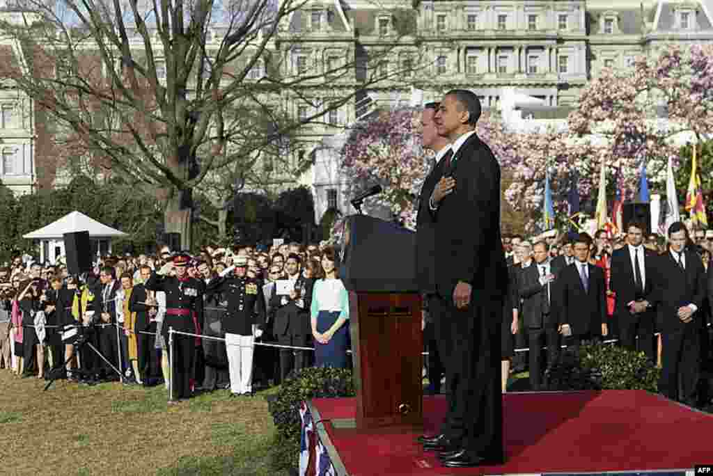 Mr. Obama and Mr. Cameron stand at attention during the playing of the national anthems during an arrival ceremony on the South Lawn of the White House. (AP)