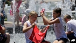 FILE - Children play in the fountain in the scorching heat in Melbourne, Australia, Jan. 16, 2014. 