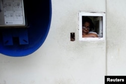 An employee peers from a window at a pharmacy in Havana, Dec. 1, 2017.