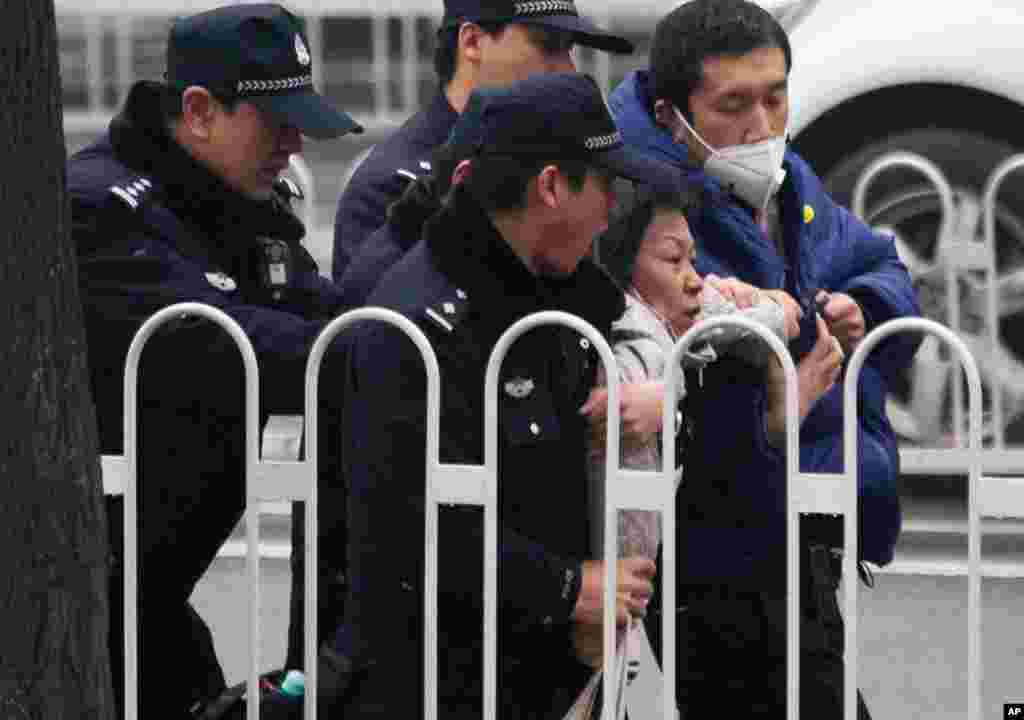 Police officers take away a supporter of rights lawyer Pu Zhiqiang near the Beijing Second Intermediate People&#39;s Court during his trial in Beijing, China. Pu went on trial on charges of provoking trouble with commentaries on social media that were critical of the ruling Communist Party.