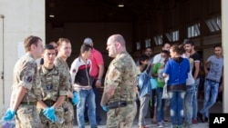 Syrian migrants are temporarily housed at a warehouse after coming ashore at RAF base Akrotiri, Cyprus, Oct. 21, 2015.