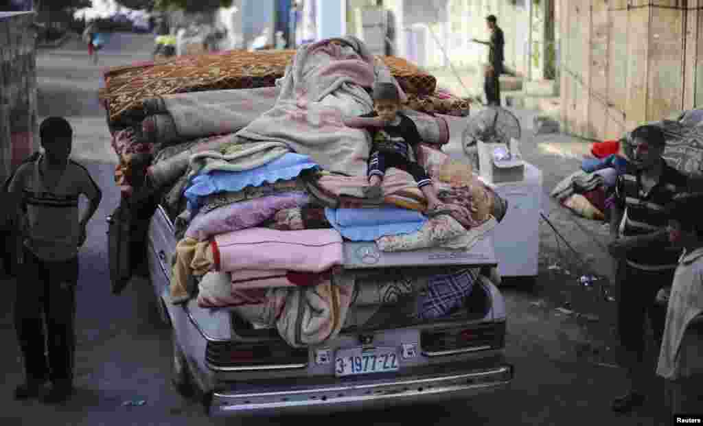 A Palestinian boy sits atop a car loaded with his family&#39;s belongings near their house, which was hit by an air strike, in Rafah in the southern Gaza Strip, Aug. 26, 2014.