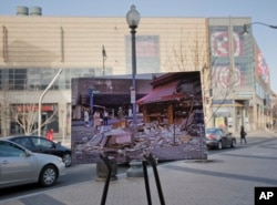 April 6, 1968, photo of looted and burned buildings is placed on a easel at the present day shopping area near 14th and Kenyon Streets in northwest Washington, on March 25, 2018. The April 4, 1968, assassination of Martin Luther King Jr. sparked rioting across neighborhoods in Washington.