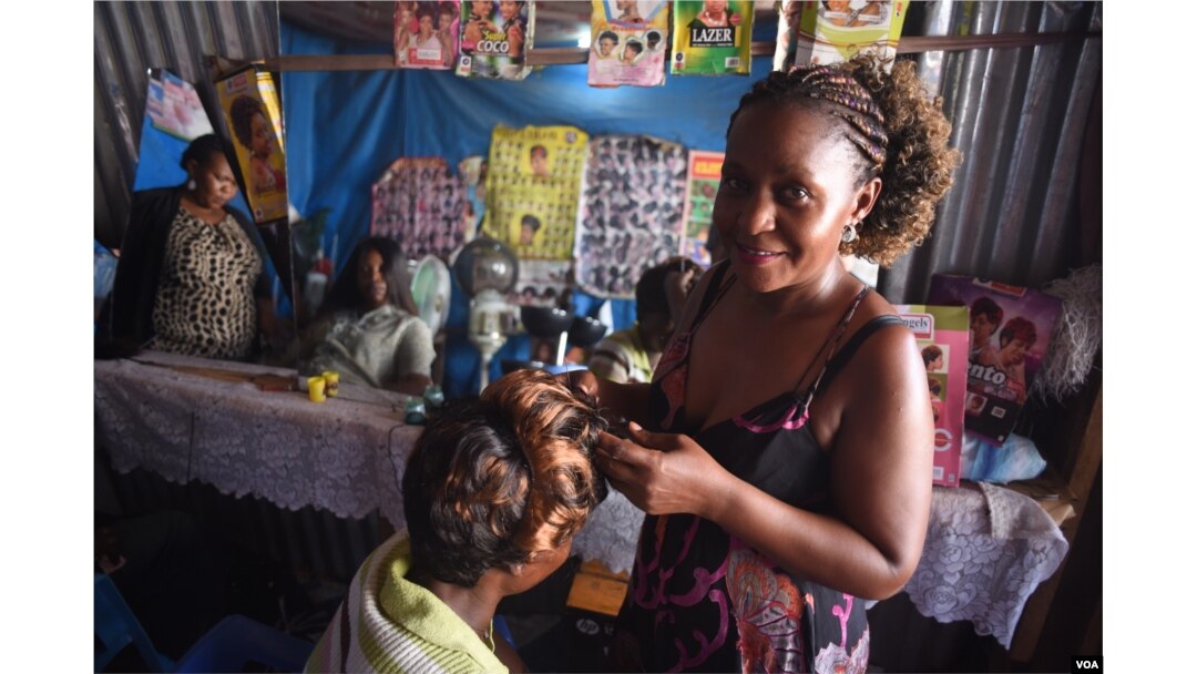 Mary Sanyu, a hairdresser, poses for a photograph in her salon at Konyo Konyo market in Juba, South Sudan on April 15, 2016. (VOA/J. Patinkin)
