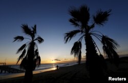 FILE - A woman walks on the beach at sunset in the Mediterranean resort town of Belek in Antalya, Turkey, Jan. 8, 2016.