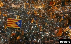 FILE - Protesters hold the lights of their mobile phones as they wave Estelada flags during a demonstration called by pro-independence associations asking for the release of jailed Catalan activists and leaders, in Barcelona, Spain, Nov. 11, 2017.