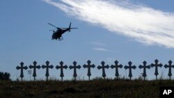 A law enforcement helicopter flies over crosses placed near the scene of a shooting at the First Baptist Church of Sutherland Springs in Sutherland Springs, Texas, Nov. 6, 2017.