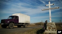 FILE - A truck drives by an Orthodox cross with a sign reading Save and Guard, at a memorial to the victims of the Malaysian Airlines MH17 plane crash, near the village of Hrabove, eastern Ukraine, October 13, 2015 .
