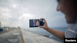 Artist Dariel Llerandis, 31, shows his wife and his 6-month-old daughter who live in Miami, as he speaks to them using the internet at a Wi-Fi hotspot in Havana, Sept. 22, 2015.