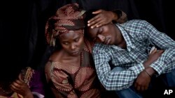 Bizimana Emmanuel, who was born two years before the genocide, is consoled by an unidentified woman while attending a ceremony to mark the tragedy's 20th anniversary, Kigali, April 7, 2014.