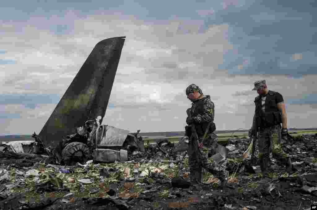 Pro-Russian fighters walk past remnants of a downed Ukrainian army aircraft Il-76 at the airport near Luhansk, Ukraine, June 14, 2014.