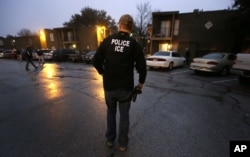FILE - U.S. Immigration and Customs Enforcement agents enter an apartment complex looking for a specific immigrant convicted of a felony.