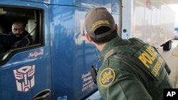 FILE - Border Patrol agent Eric Mendoza speaks to the driver of a tractor-trailer waiting to pass through the Laredo North vehicle checkpoint in Laredo, Texas, on Feb. 2, 2018. 