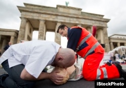 Paramedis memperagakan cara memberikan pernafasan buatan atau CPR di depan Gerbang Bradenburg di Berlin, Jerman, 10 Agustus 2012. (Foto: AP)