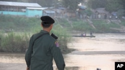 Thai soldier watches people who fled fighting take boats to and from Burma, Mae Sot, Thailand, 09 Nov 2010