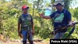 Rosek Nursahid (kanan) dari Profauna memberi pengertian mengenai larangan berburu di hutan lindung Sendiki di Malang selatan kepada seorang warga (topi merah) yang kedapatan berburu di dalam hutan (Foto: VOA/Petrus Riski).