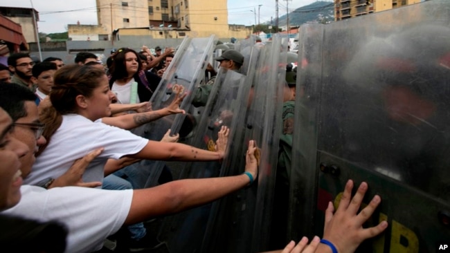 Los estudiantes universitarios empujan los escudos antidisturbios de los oficiales de la Guardia Nacional Bolivariana Venezolana durante una protesta fuera del Tribunal Supremo en Caracas, Venezuela, el viernes 31 de marzo de 2017.