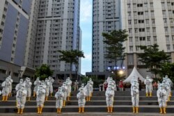 Petugas kesehatan mengenakan APD memainkan angklung, alat musik tradisional yang terbuat dari bambu untuk merayakan ulang tahun pertama Rumah Sakit Darurat COVID-19 Wisma Atlet di Jakarta, 23 Maret 2021. (Foto: Antara/M Risyal Hidayat via REUTERS)