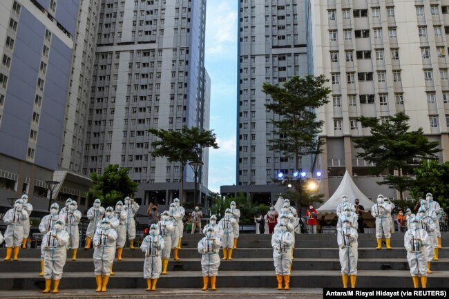 Petugas kesehatan mengenakan APD memainkan angklung, alat musik tradisional yang terbuat dari bambu untuk merayakan ulang tahun pertama Rumah Sakit Darurat COVID-19 Wisma Atlet di Jakarta, 23 Maret 2021. (Foto: Antara/M Risyal Hidayat via REUTERS)