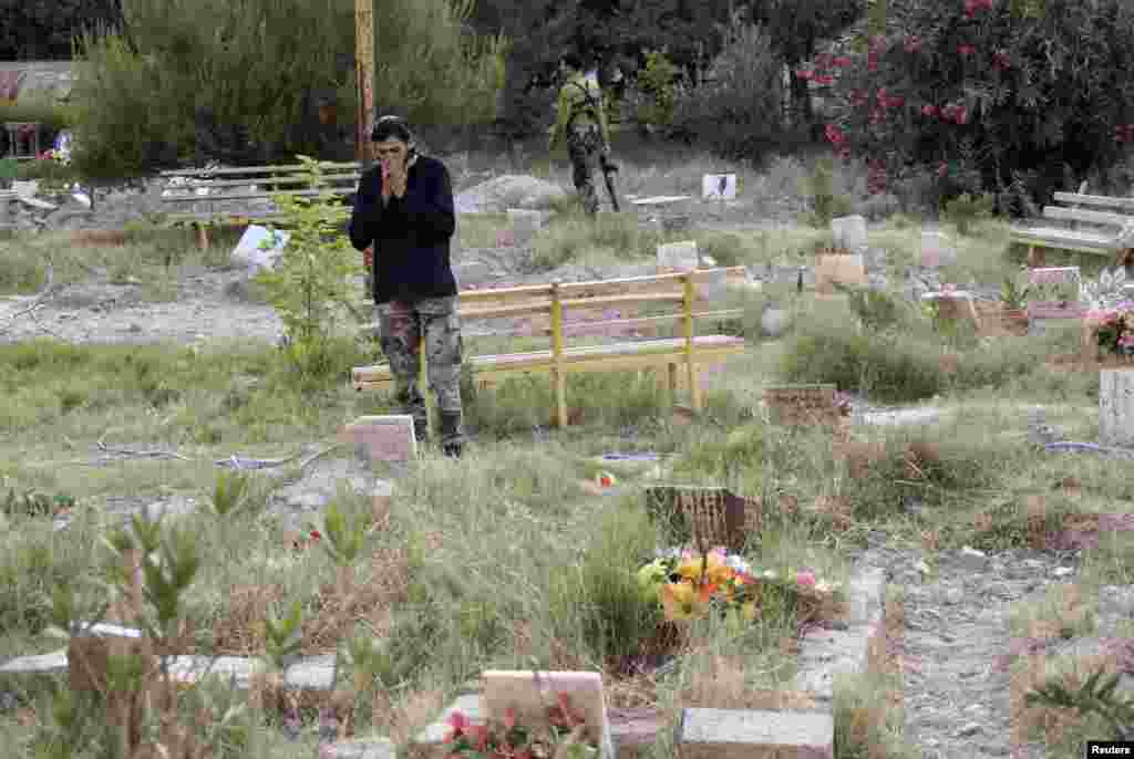 Seorang anggota Tentara Pembebasan Suriah di kuburan sesama pemberontak di sebuah pemakaman di Deir el-Zor (16/5).