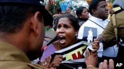 Sri Lankan policemen try to control ethnic Tamil people, whose relatives are missing, during a protest outside a public library where British Prime Minister David Cameron was meeting Tamil leaders, in Jaffna, northern Sri Lanka, Nov.15, 2013.