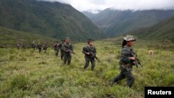 FILE - Members of the 51st Front of the Revolutionary Armed Forces of Colombia (FARC) patrol in the remote mountains of Colombia, Aug. 16, 2016. 