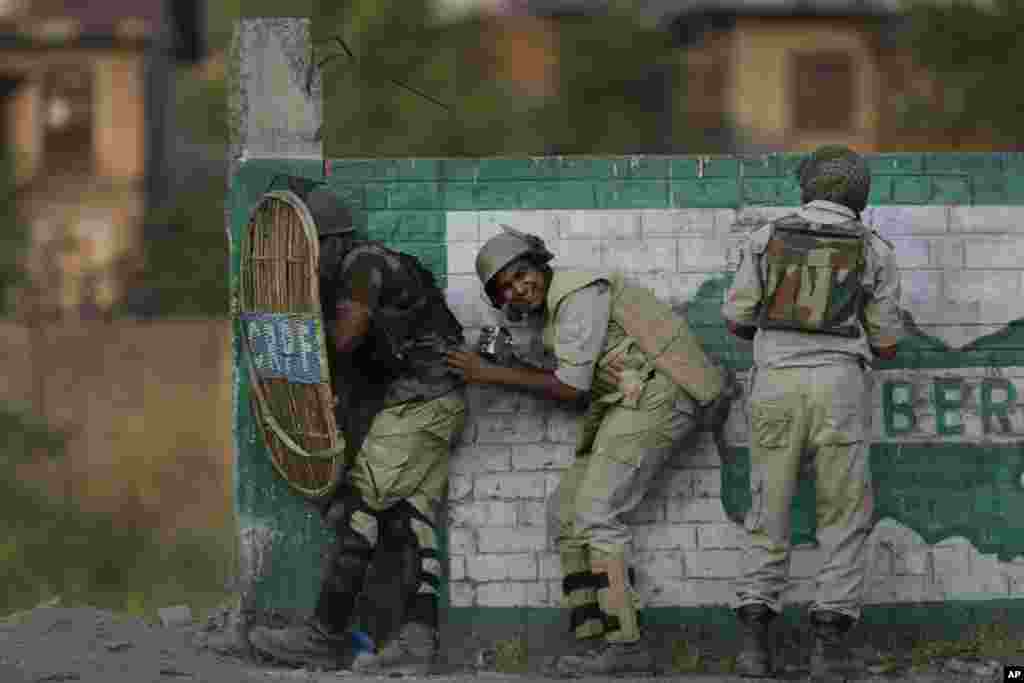 Indian paramilitary soldiers take shelter during clashes with Kashmiri stone throwers in Srinagar, Indian-controlled Kashmir.