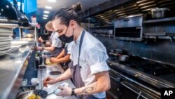 FILE - Sebastian Cacho cooks in the kitchen at Gotham restaurant on Dec. 14, 2021, in New York. 