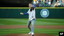 Singer and hip-hop artist Macklemore throws out the first pitch of a baseball game between the Seattle Mariners and the Kansas City Royals, Friday, April 29, 2016, in Seattle.