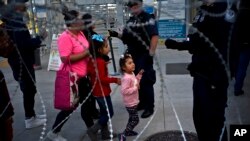Un grupo de peatones pasan vallas de concertina en un cruce fronterizo legal hacia Estados Unidos donde oficiales revisan los documentos de las personas que entran hacia el país desde Tijuana, México, el lunes 19 de noviembre del 2018. 